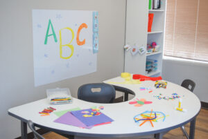 Classroom space containing a semi-circle desk, whiteboard and bookshelf