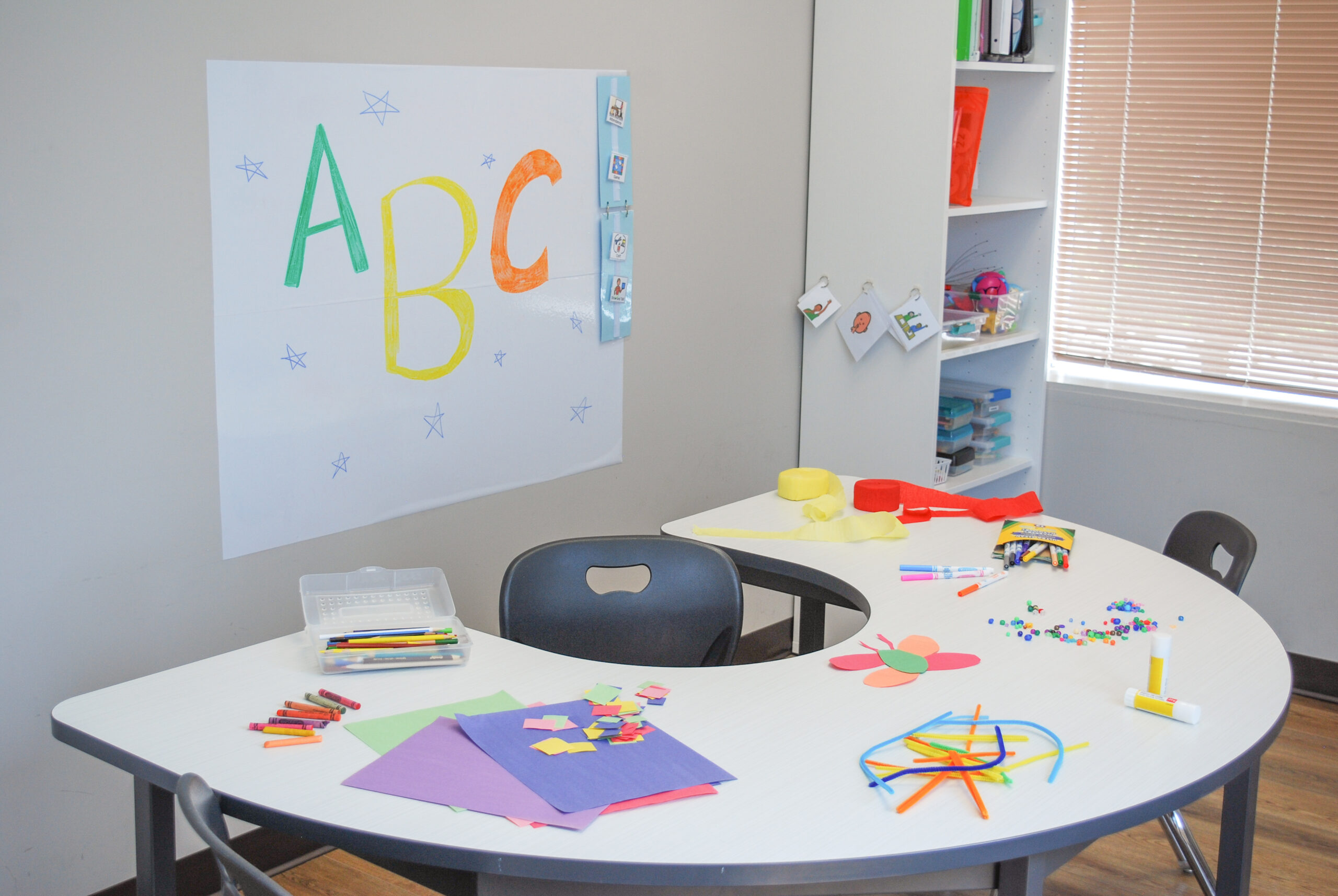 Classroom space containing a semi-circle desk, whiteboard and bookshelf