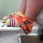Close-up of feet on a stool in front of a toilet